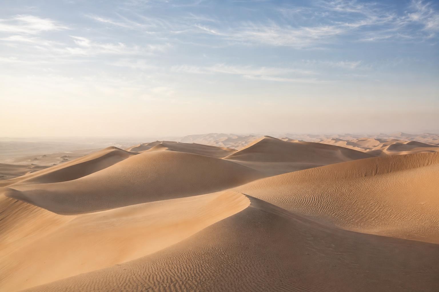 Lone figure walking the Omani dunes at golden hour